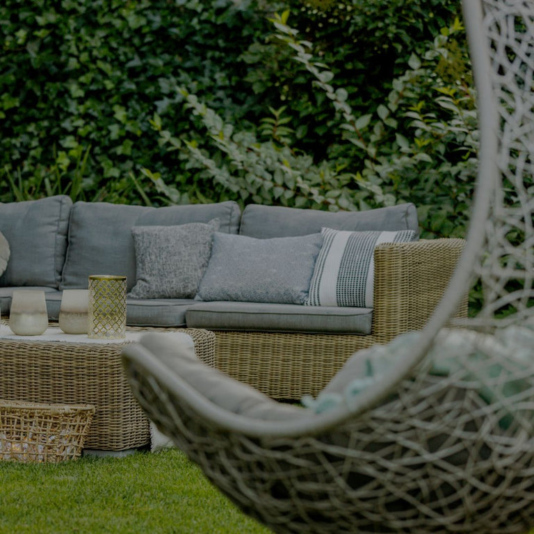 Outdoor patio set with a sectional sofa, chairs, and coffee table in a garden setting.